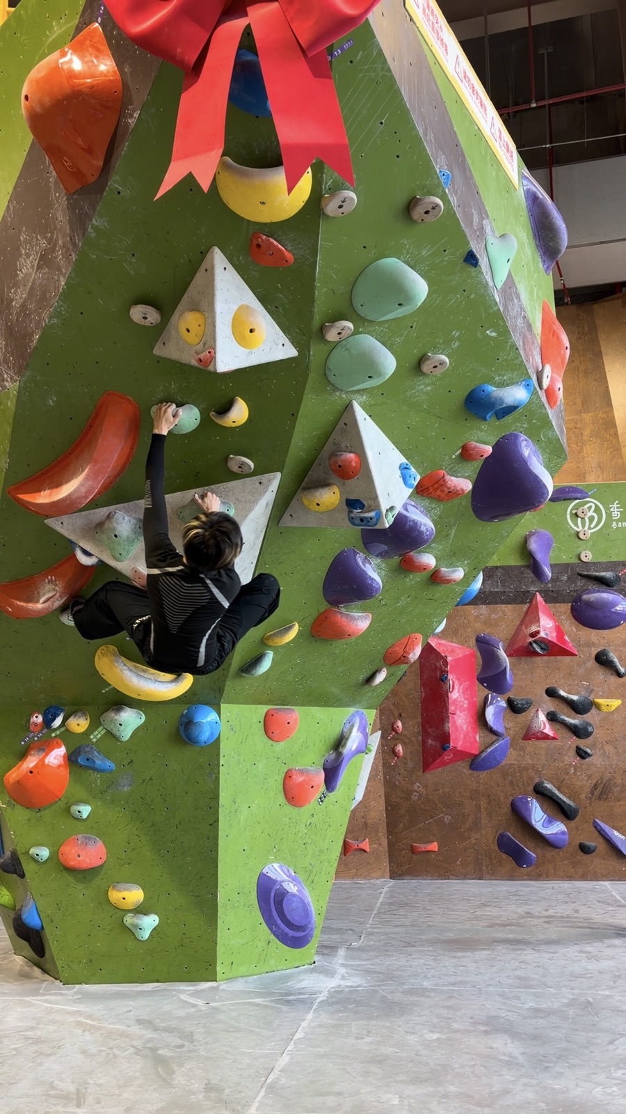 Zhuohan working through a colorful indoor bouldering problem