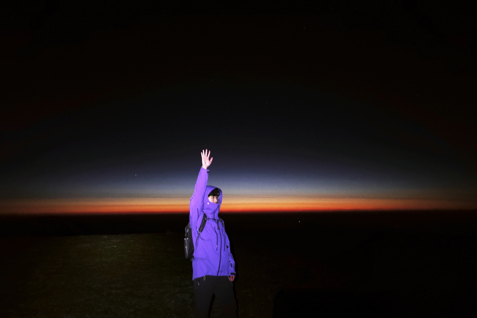 Zhuohan on a dark ridgeline beneath a vivid band of twilight