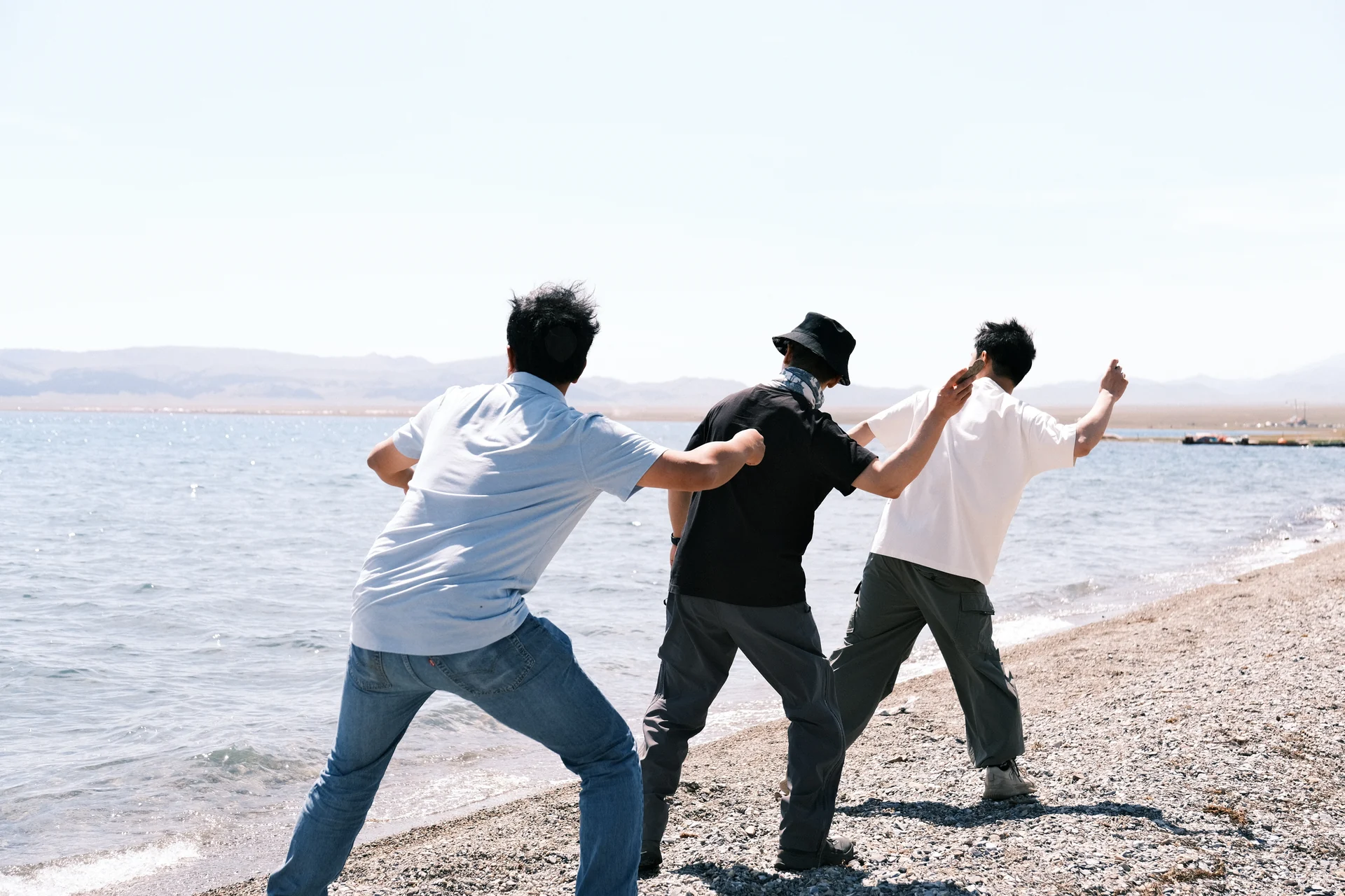 Three friends standing together at the shore of a lake in Xinjiang